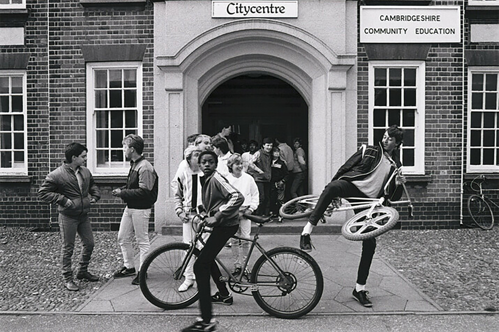 Members of the Friday Club crowd around the entrance of the City Centre building as they wait for the youth club to be opened, Peterborough, 1985. Russell Boyce / Museum of Youth Culture